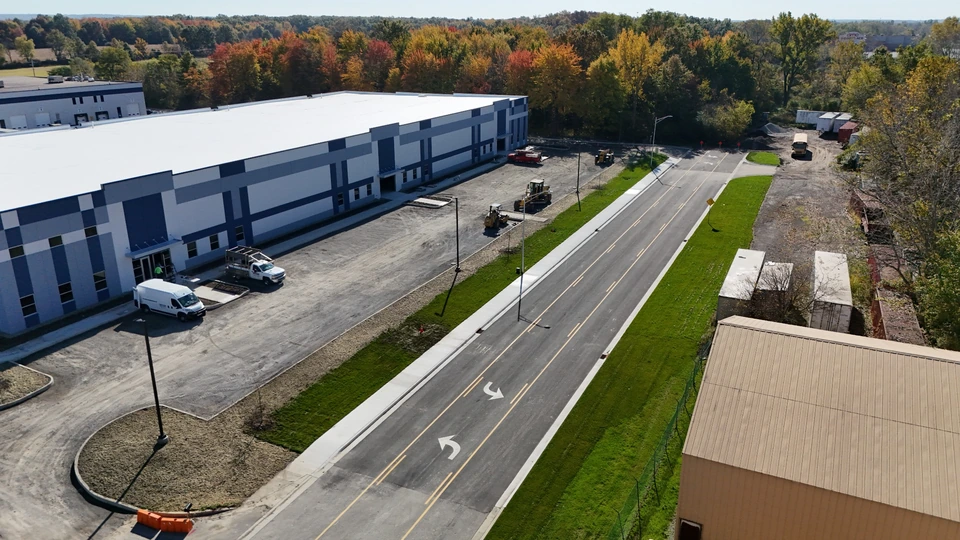 Aerial view along Ameriplex Drive Phase 2 with pavement markings, sidewalks, and autumn trees · October 23, 2026
